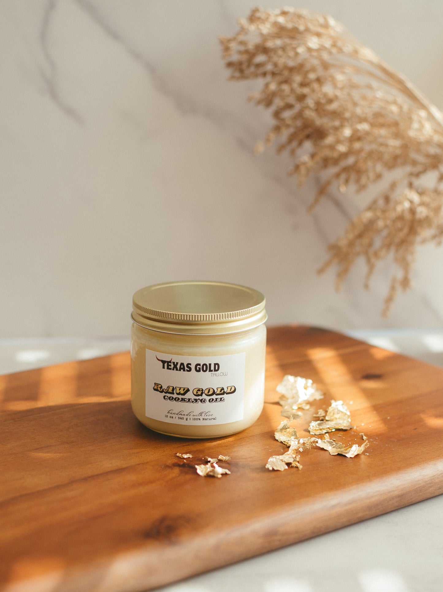 Texas Gold Tallow Raw Gold Cooking oil Beef Tallow on a wooden cutting board with gold flakes with a white marble background 