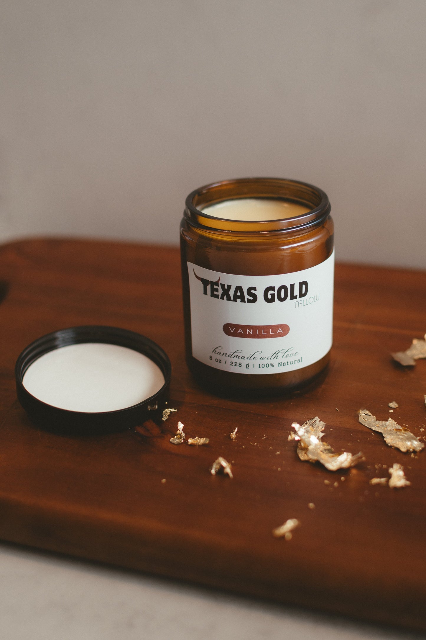 Texas Gold Tallow grass fed and grass finished beef tallow balm infused with real vanilla beans in an 8oz glass jar on wood with gold flakes