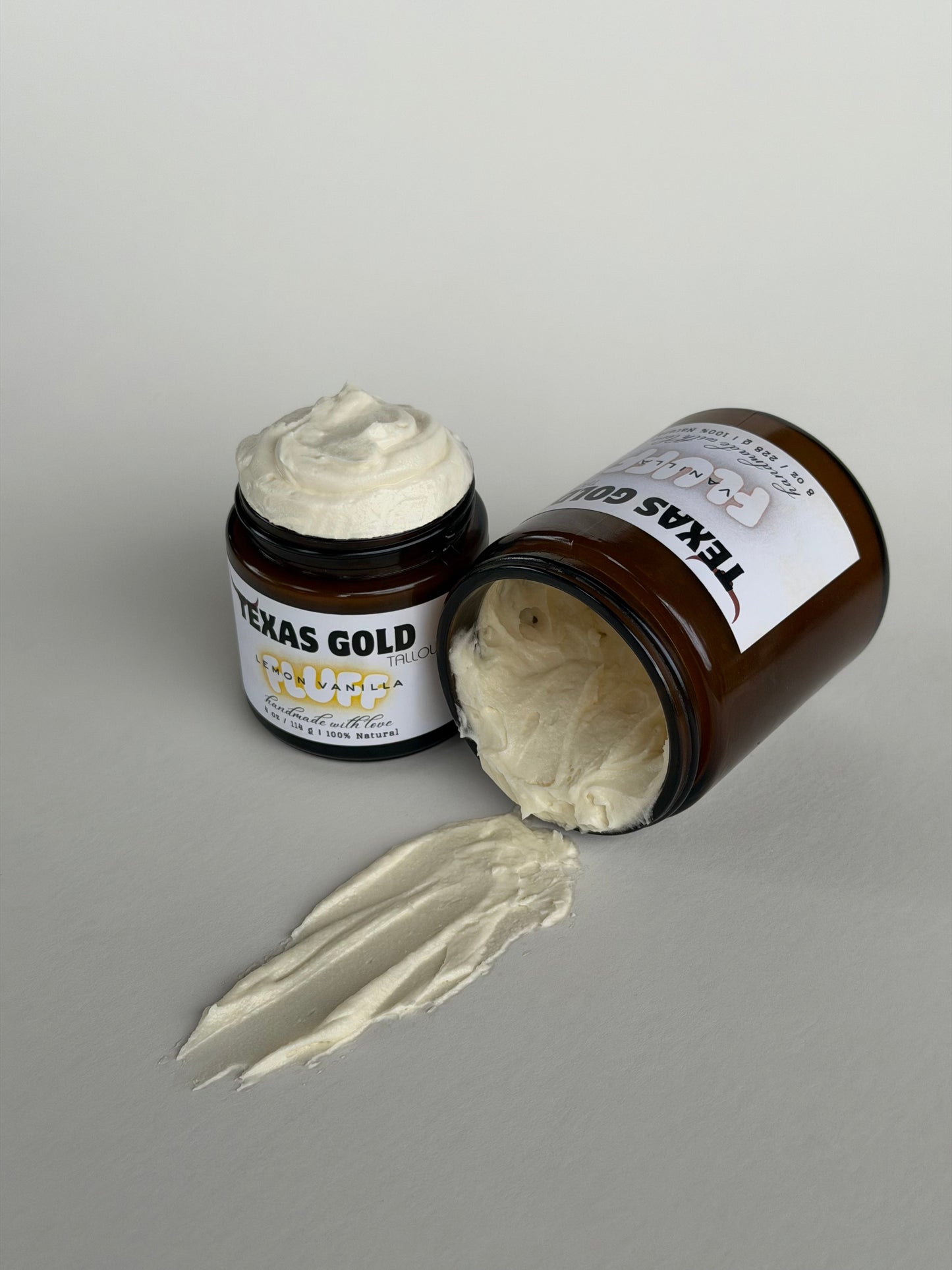 Texas Gold Tallow Lemon Vanilla FLUFF whipped tallow balm and Vanilla FLUFF whipped tallow balm spilling out on a white background
