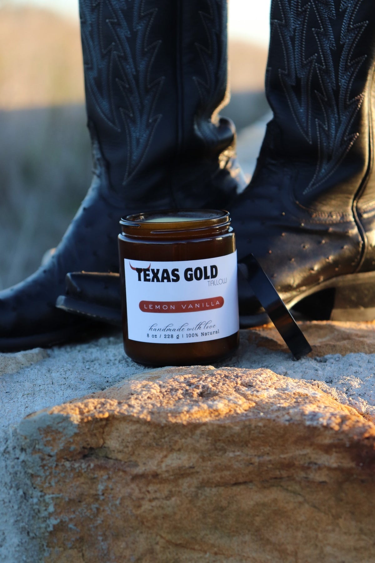 Texas Gold Tallow lemon vanilla balm on a rock with black boots in the background