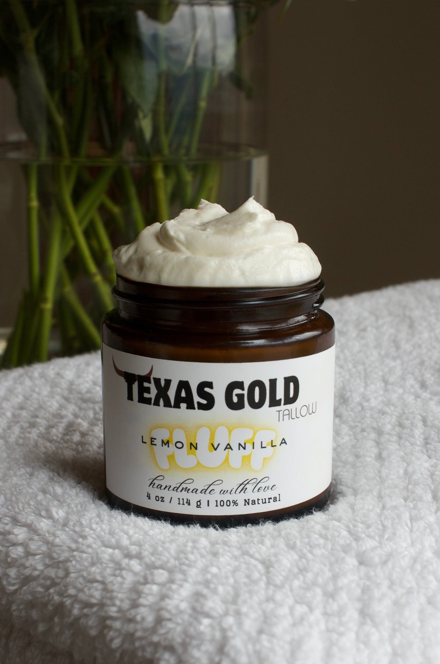 TExas Gold Tallow Lemon vanilla FLUFF tallow coming out of the jar on a white towel with flower stems in the back