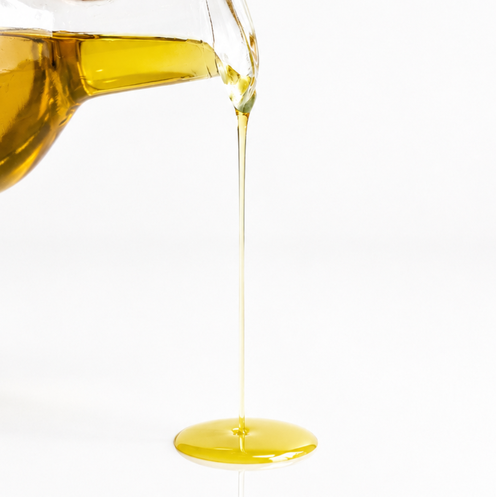 organic cold pressed jojoba oil being poured out of glass bottle