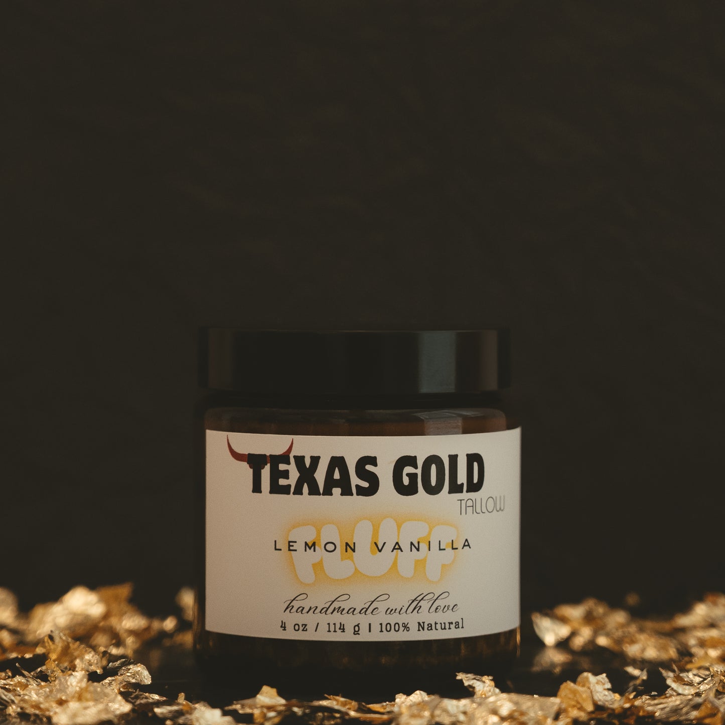 Texas Gold Tallow lemon vanilla fluff, a whipped tallow inside a 4 ounce glass jar with black background and gold flakes