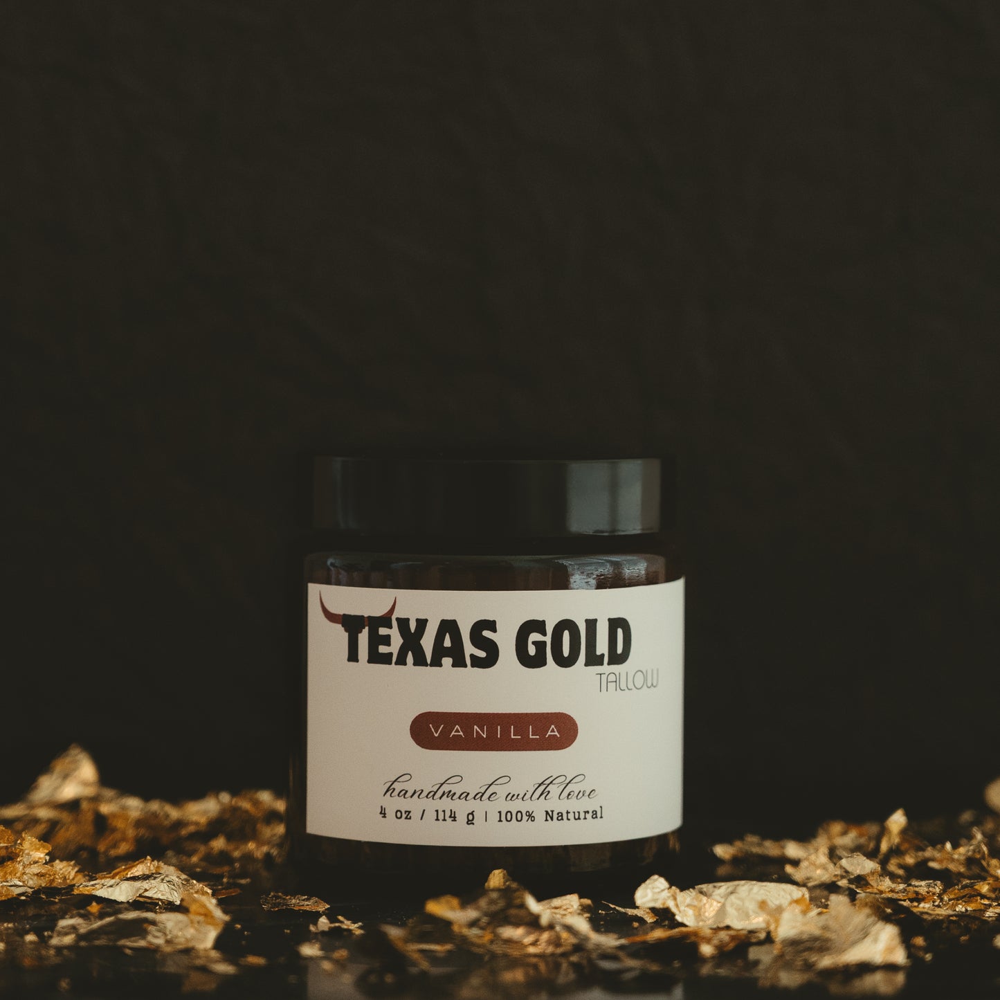 Texas gold tallow vanilla balm in a 4 ounce glass jar with black background and gold flakes
