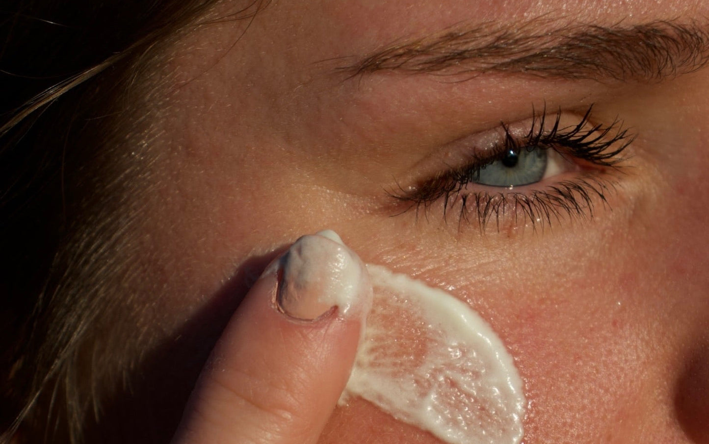 Close-up of a person applying Texas Gold Tallow to their face with a finger.